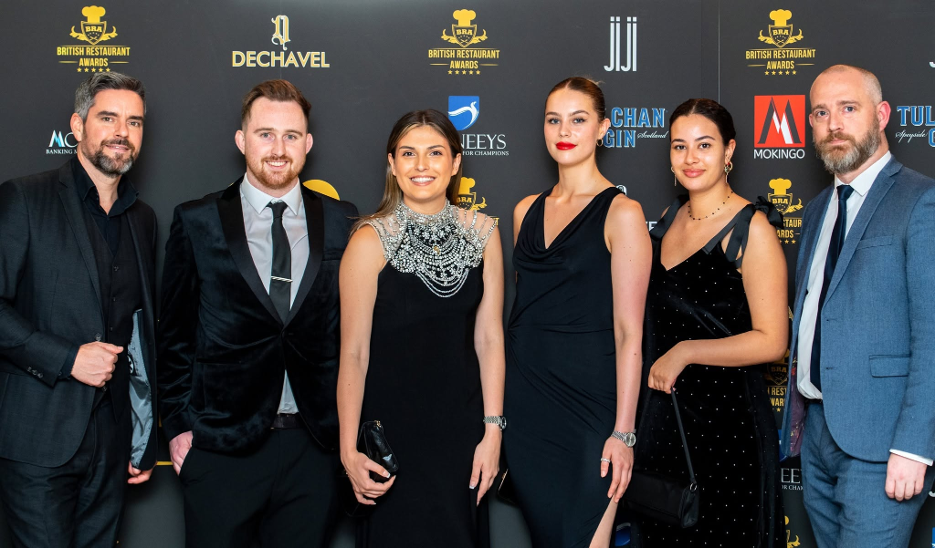 Guests on the British Restaurant Awards red carpet in front of the official branded backdrop