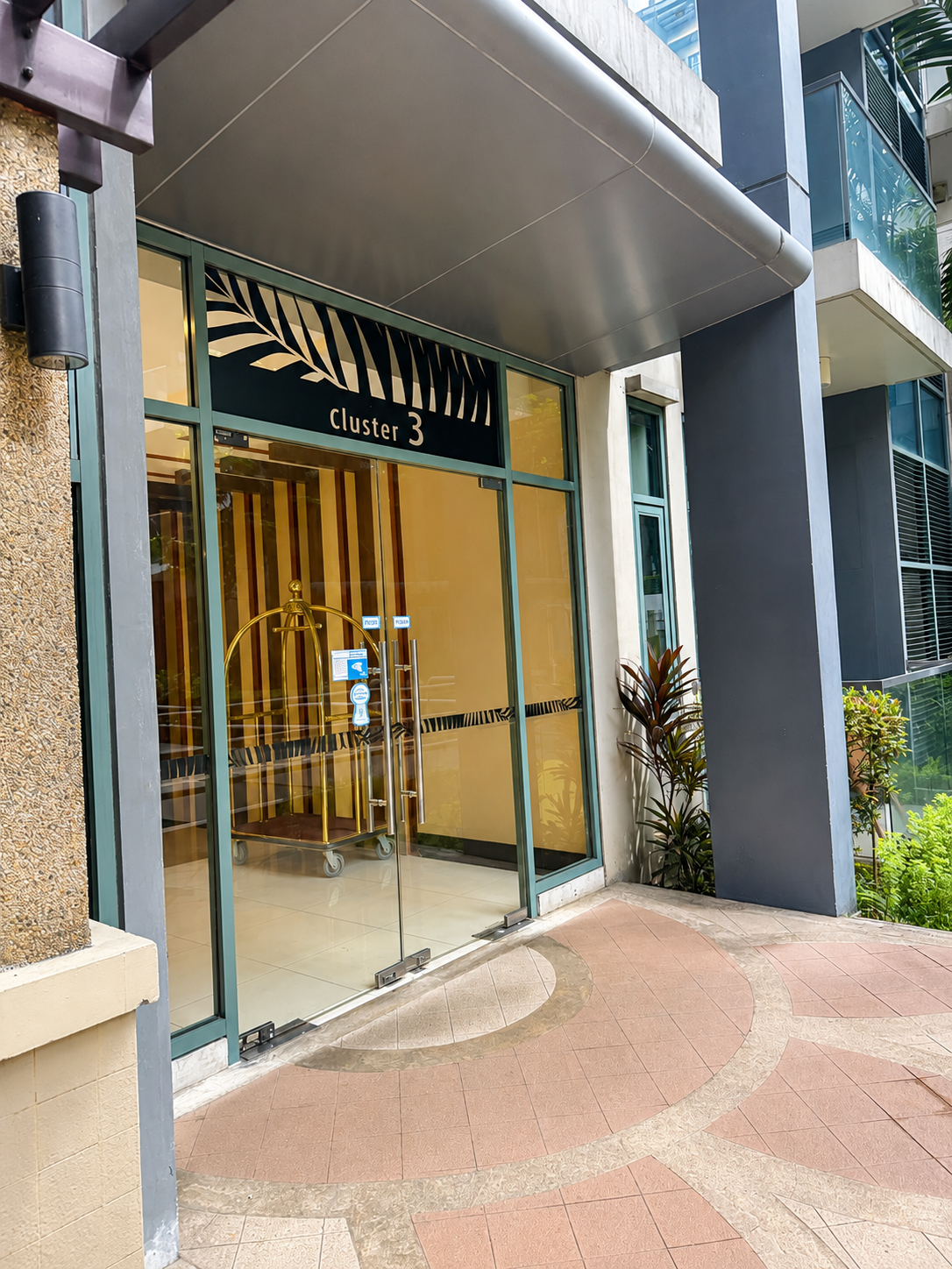 Cluster 3 building entrance with glass doors and palm-leaf motif at Two Palm Tree Villas