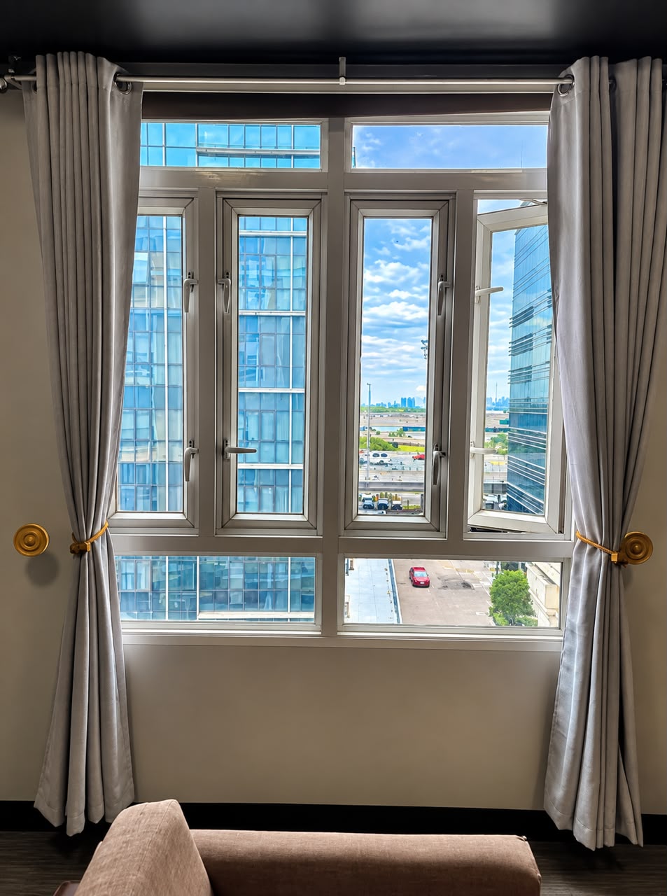 Window view onto nearby Newport City high-rise buildings with light grey curtains