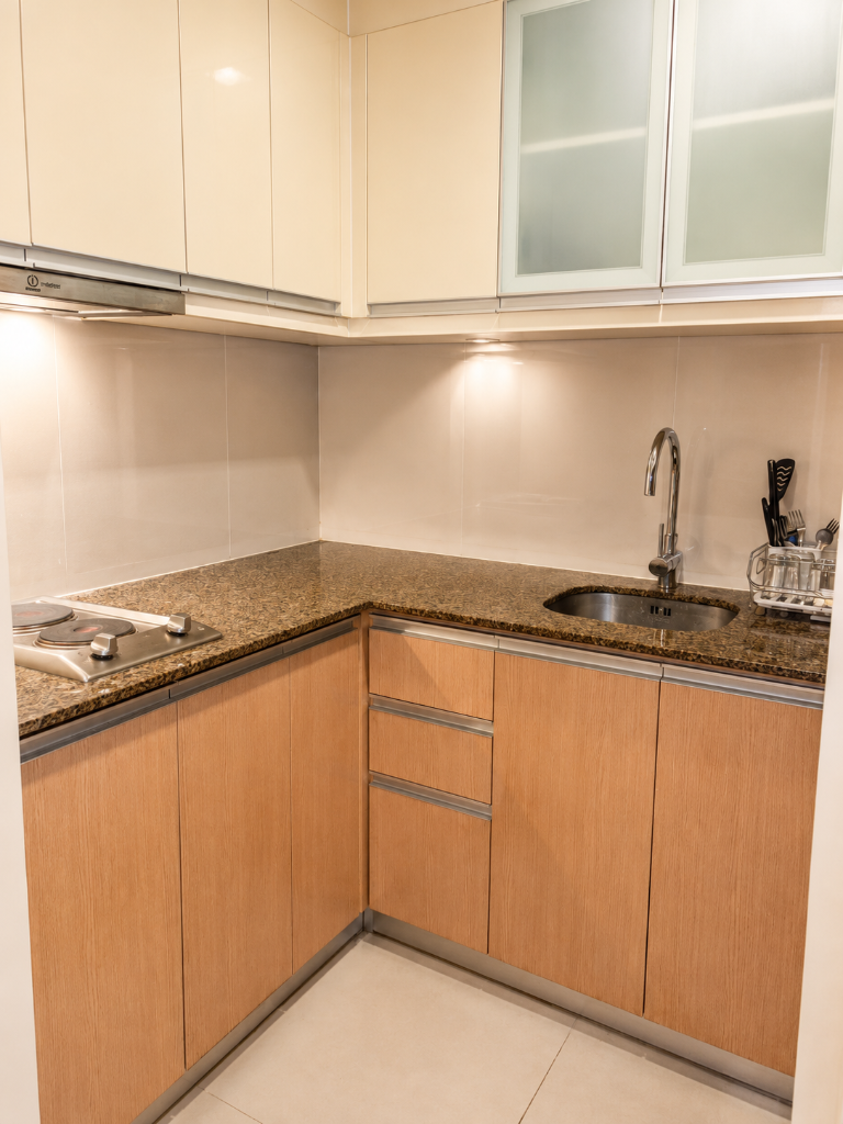 L-shaped kitchen with granite countertops, electric hob, deep sink, and full cabinet storage