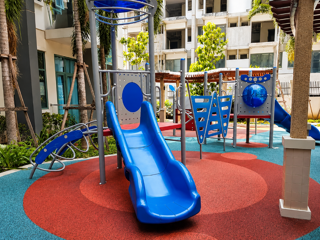 Children's playground with blue slide and climbing structures in a landscaped courtyard