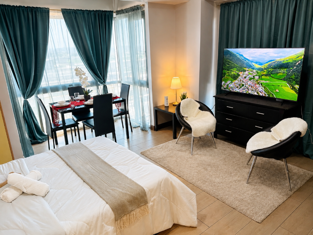 Briana's Haven One — studio with king bed, dining area, large TV, and teal curtains at Two Palm Tree Villas