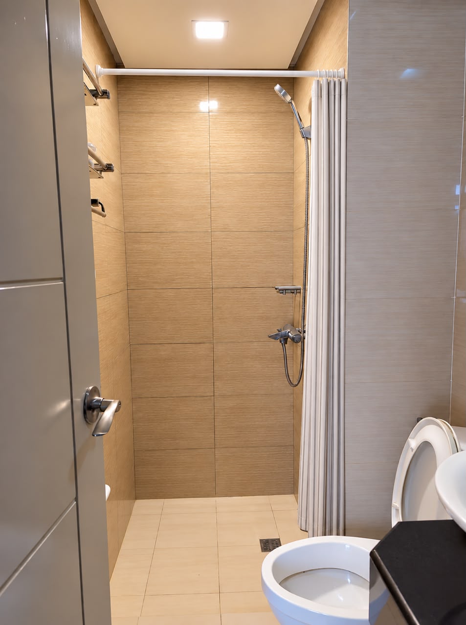 Bathroom with tan tiles, glass shower area, and white shower curtain