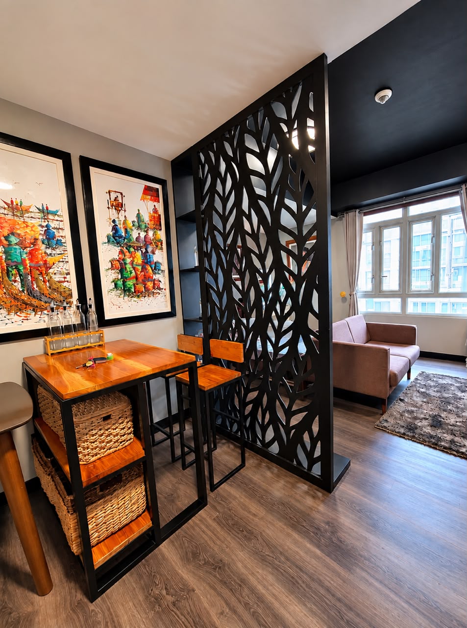 Black laser-cut leaf-pattern room divider separating the entry and kitchenette from the living space