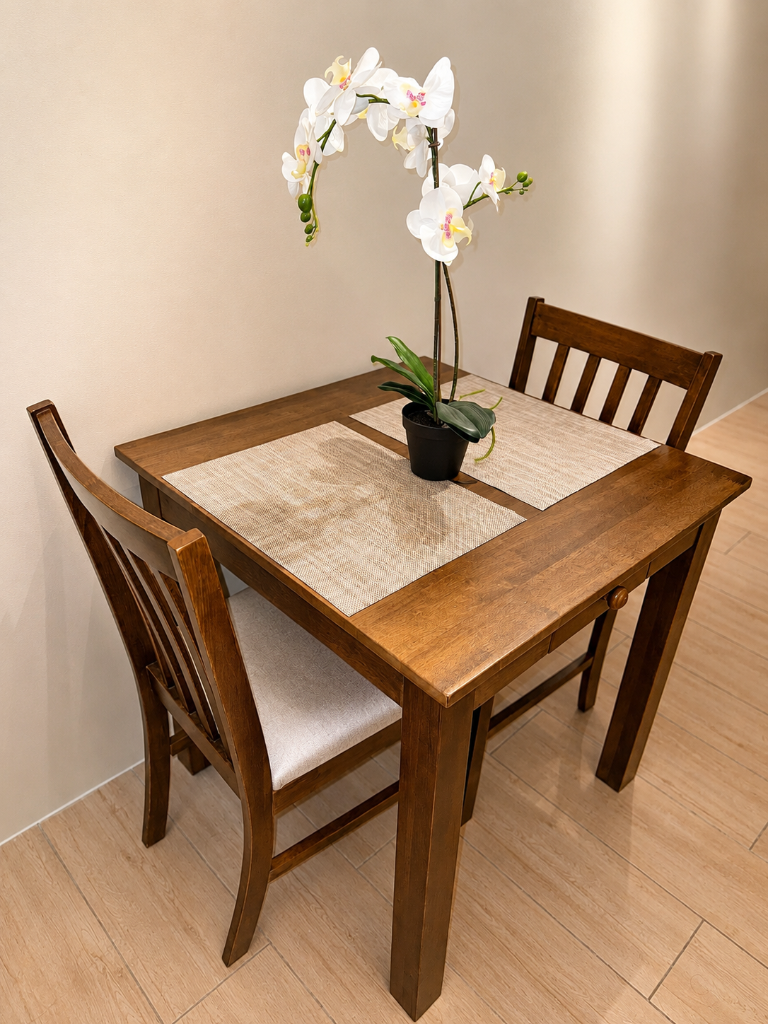 Wooden dining table for two with white orchid centerpiece and linen placemats