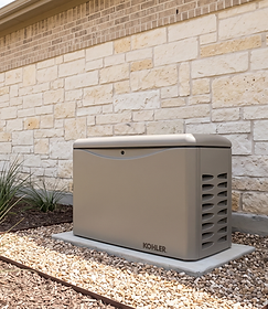Kohler standby backup generator on a gravel bed beside a stone-veneer Houston home