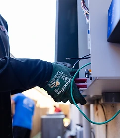 GenPro electrician wearing safety gloves working on an open residential electrical panel in Houston