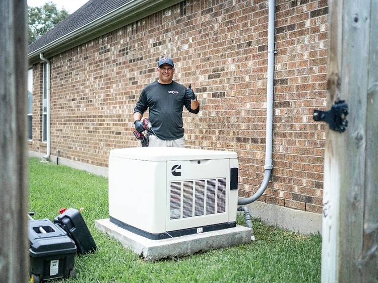 Cummins standby generator with technician giving a thumbs up