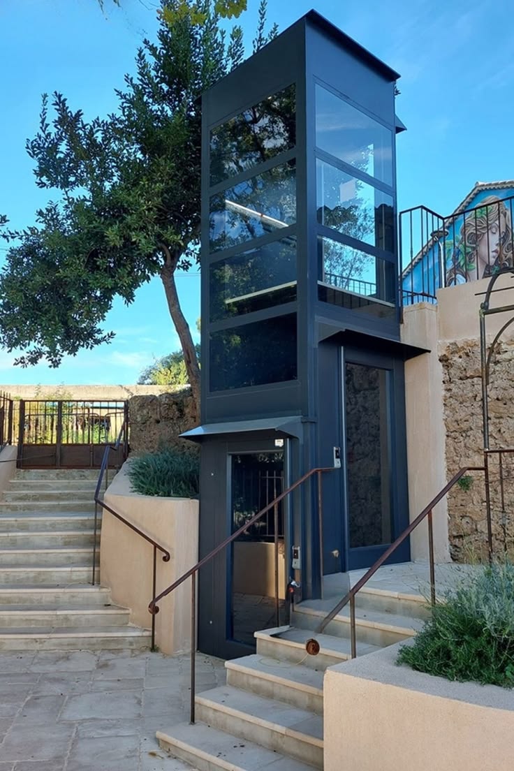 Lift — plataforma vertical junto a escalera de piedra