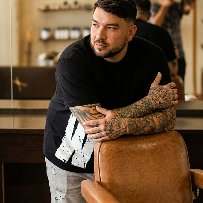 Barbero de Why Not Barbershop apoyado en una silla de barbería vintage en su local de Consell de Cent, Barcelona