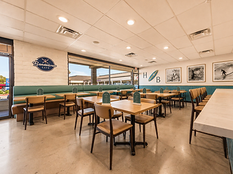 Hospitality interior design by Studio Fridae — Bandoleros Café in Huntington Beach, CA with teal wainscoting, HB surfboard wall art, and tan leather booth seating