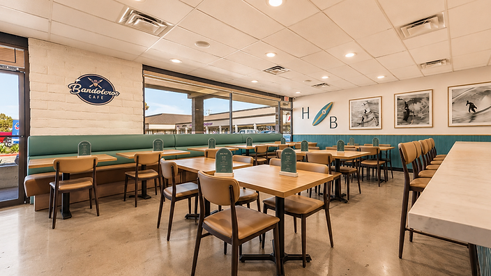 Bandoleros Café logo on white painted brick wall with teal wainscoting and dining area in Huntington Beach, CA — hospitality interior design by Studio Fridae