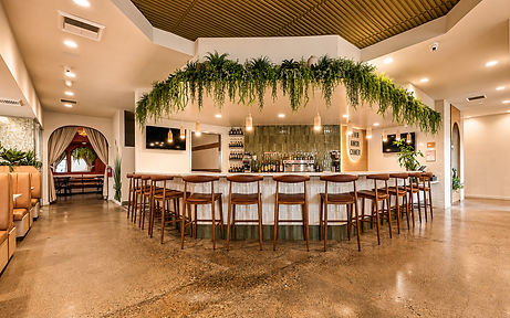 Bar area of Bandoleros Cafe in Cypress, CA with marble counter, wooden bar stools, hanging greenery, sage green tile, and VIVIR AMOR COMER sign — restaurant interior design by Studio Fridae