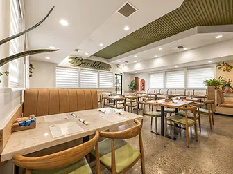 Bandoleros Cafe dining room in Cypress, CA with tufted leather booths, marble-top tables, and a brush-script Bandoleros logo — small restaurant interior design by STUDIO FRIDAE