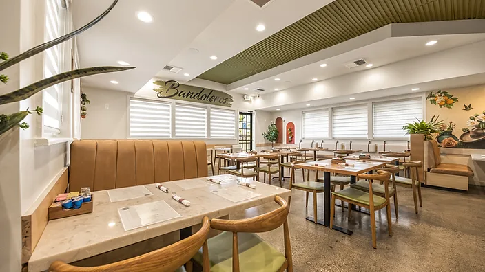 Bandoleros Cafe dining room in Cypress, CA with tufted leather booths, marble-top tables, and a brush-script Bandoleros logo — small restaurant interior design by STUDIO FRIDAE