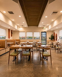 Main dining area of Bandoleros Cafe in Cypress, CA with cognac leather booths, olive green chairs, marble-topped tables, and wooden slat ceiling — hospitality interior design by Studio Fridae