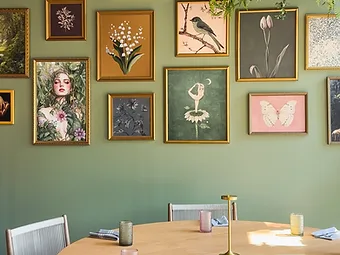Flora dining room with botanical gallery wall, round oak table, and hanging greenery — hospitality interior design in Charlotte, NC by Studio Fridae