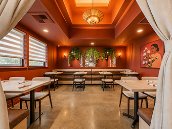 Hospitality interior design by Studio Fridae — Bandoleros Cafe in Cypress, CA dining room with brown leather banquette, hanging greenery, floral portrait, and terracotta ceiling