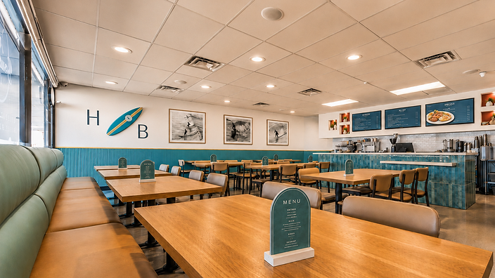 Bandoleros Café dining room in Huntington Beach, CA with teal wainscoting, HB surfboard wall art, and light wood tables — café interior design by Studio Fridae