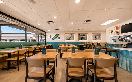 Wide dining room view at Bandoleros Café in Huntington Beach, CA with teal booth seating, surfboard décor, and black-and-white surf photography — hospitality interior design by Studio Fridae