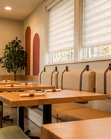 Tan leather banquette seating with terracotta arch wall decor and wooden tables at Bandoleros Cafe in Cypress, CA — hospitality interior design by Studio Fridae