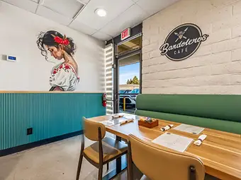 Hospitality interior design by Studio Fridae — Bandoleros Café in Huntington Beach, CA with floral mural, teal wainscoting, and sage green booth seating