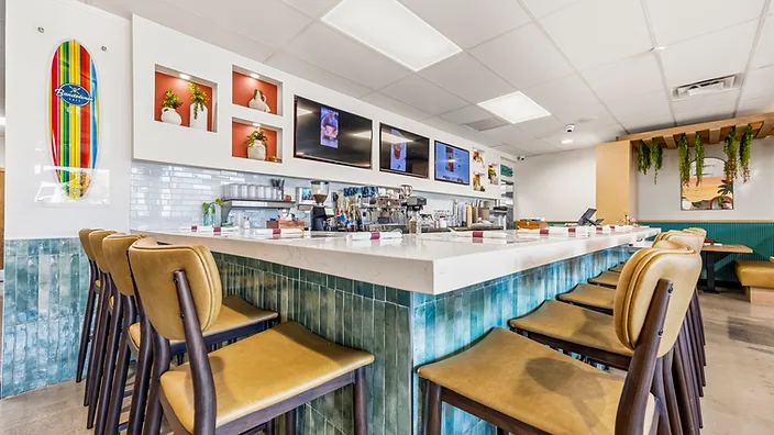 Bandoleros Café booth seating nook with tan leather banquettes and hanging greenery — hospitality interior design in Huntington Beach, CA by Studio Fridae