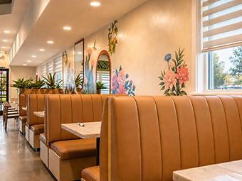 Tan channel-tufted booth seating beneath a colorful botanical mural with arched mirrors at Bandoleros Cafe in Cypress, CA — hospitality interior design by Studio Fridae