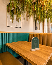 Corner booth with arched mirror and cascading greenery at Bandoleros Café in Huntington Beach, CA — café interior design detail by Studio Fridae