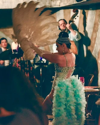 Burlesque performer with a feather fan and mint bustle at Saint Tuesday