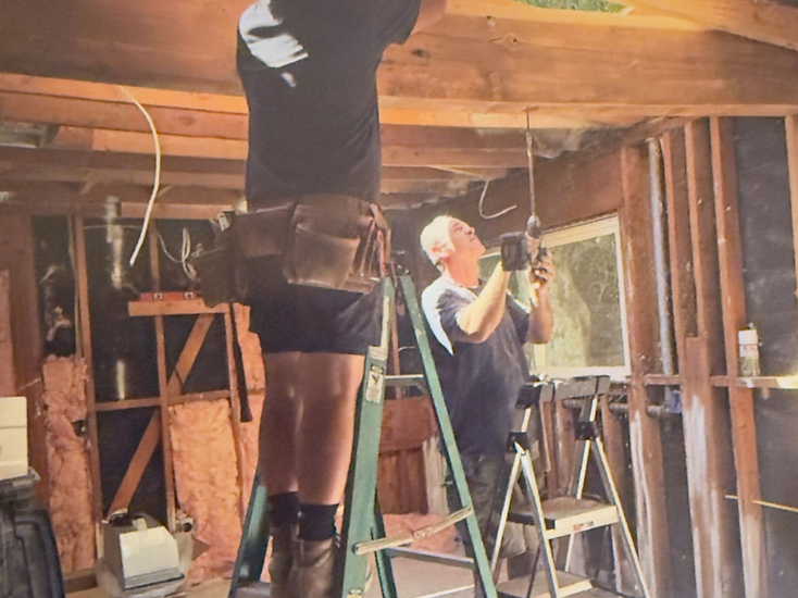 An older photograph of two family members framing and wiring a house under renovation