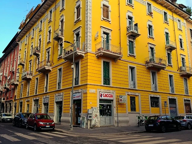 A vibrant yellow corner building with ornate balconies at a quiet intersection.