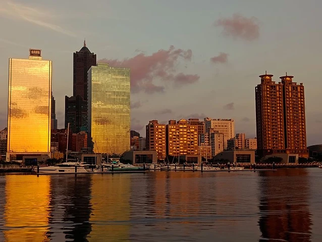 Glass-clad skyscrapers and residential towers glow in the golden hour light by water.