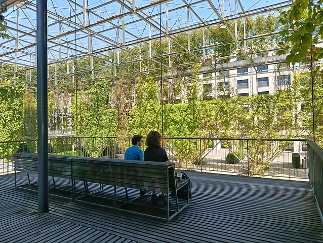 The observer captures two individuals seated on a wooden bench atop the metal grid.