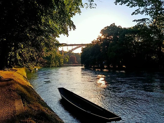 A wooden boat moored on a tranquil river with sunset light filtering through.