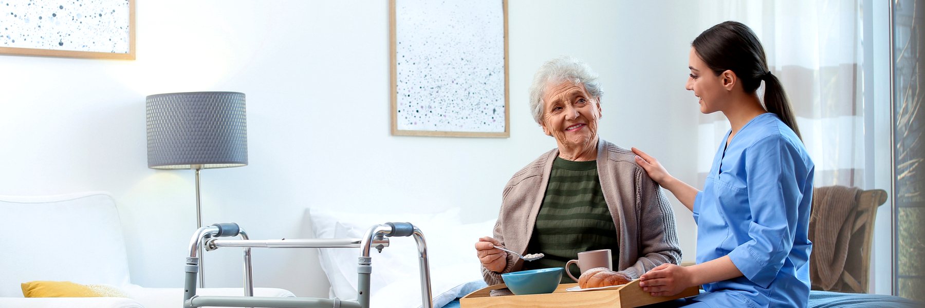 A caregiver sitting with an elderly woman at home