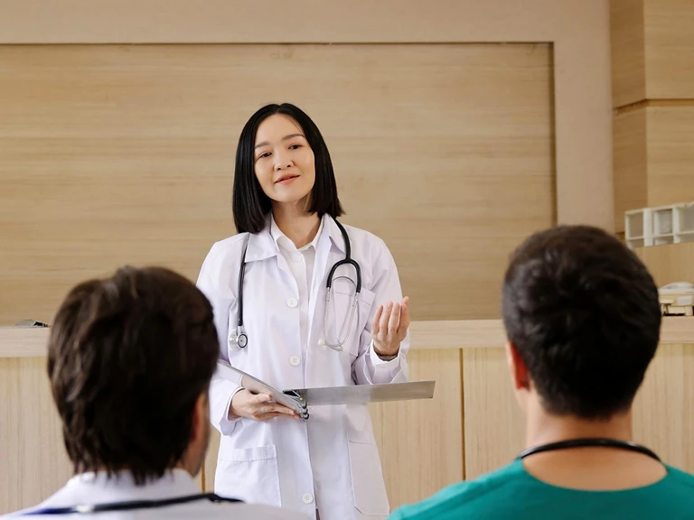 A senior clinician briefing two colleagues at a healthcare facility