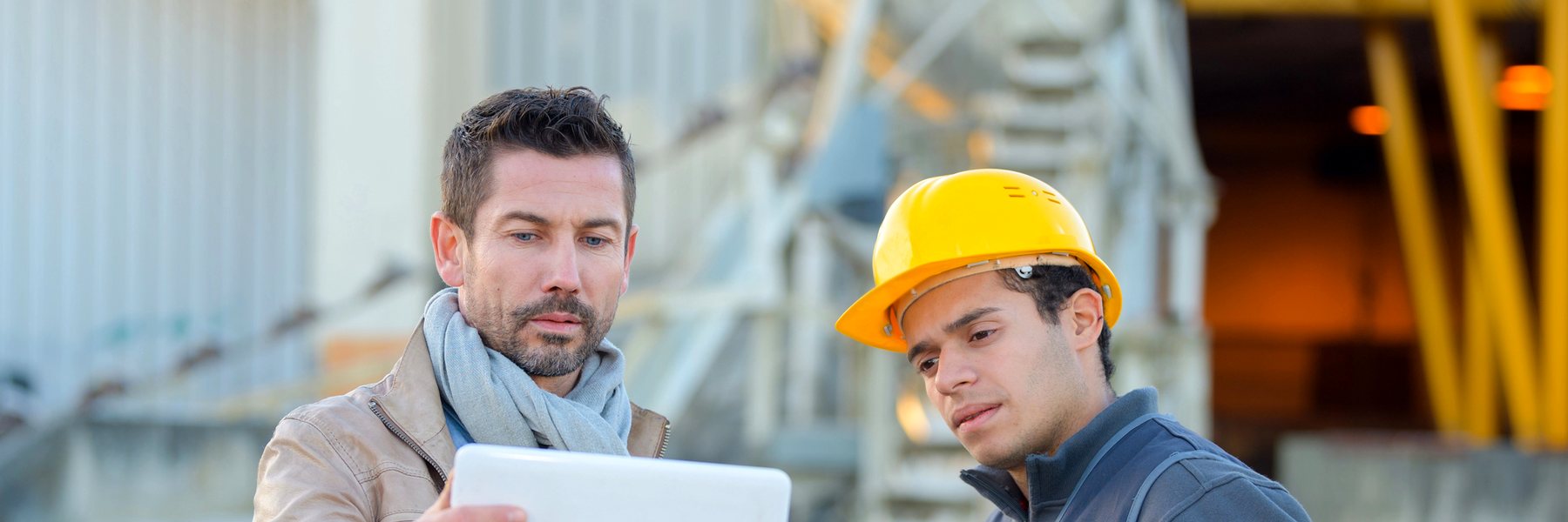 An employer and a worker reviewing plans together at a construction site