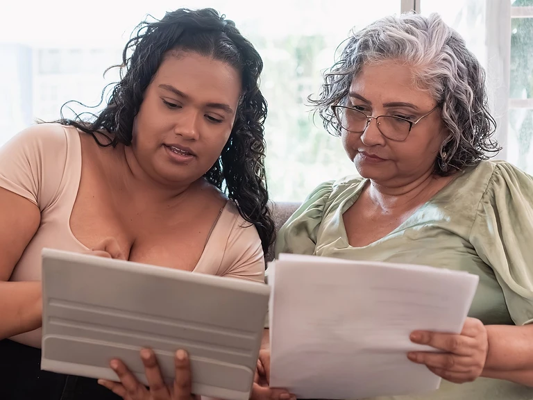A woman reviewing paperwork with her mother at home