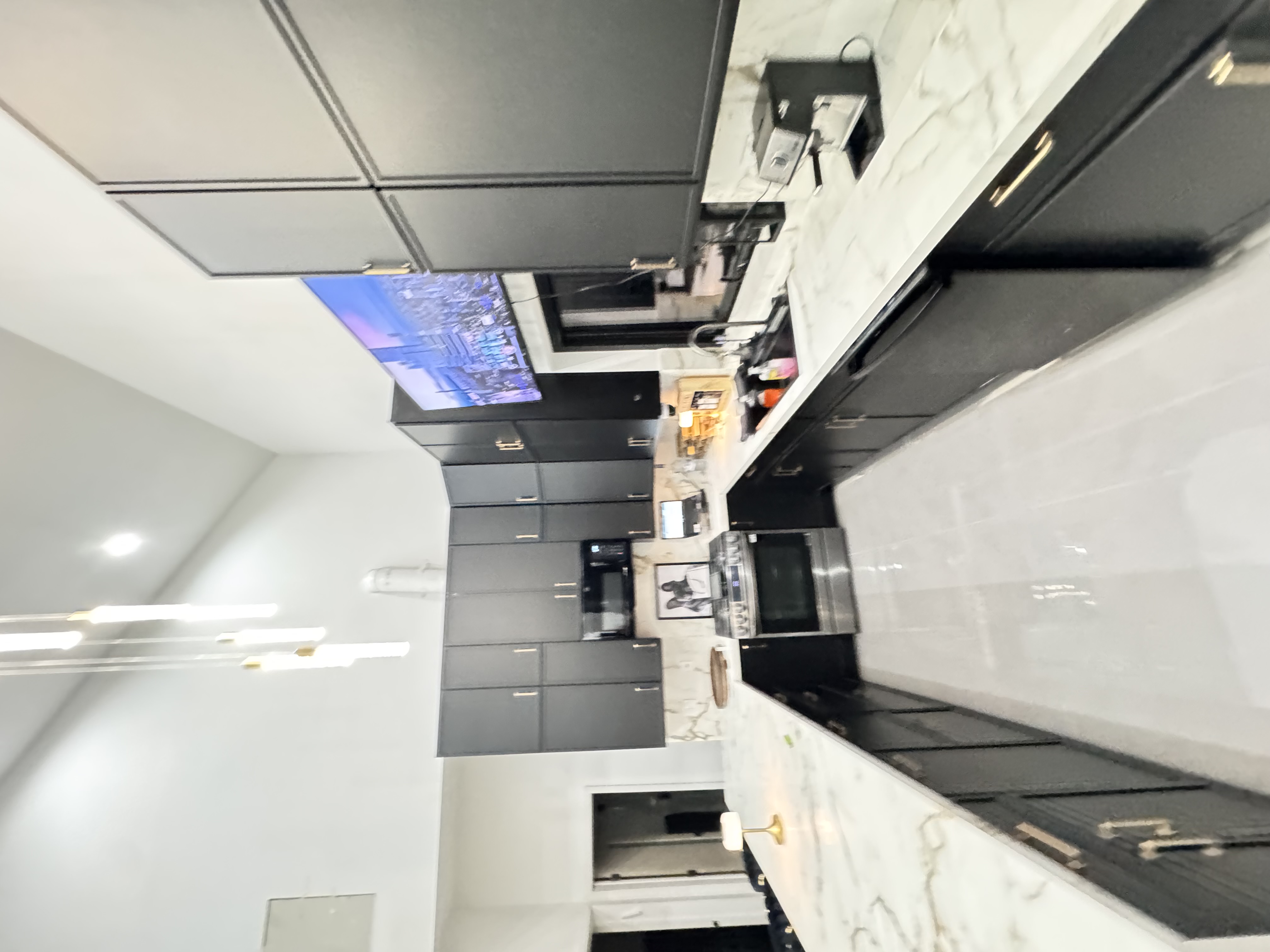 Modern kitchen with dark cabinetry, gold multi-pendant fixture, and marble waterfall island
