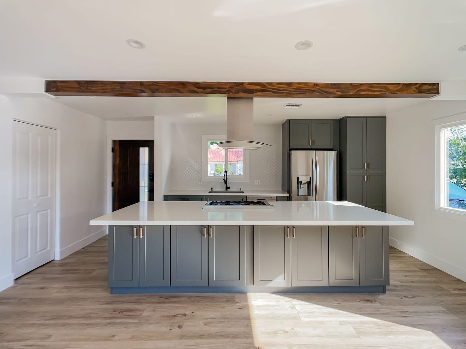 Kitchen with grey-blue island, gold hardware, and herringbone backsplash