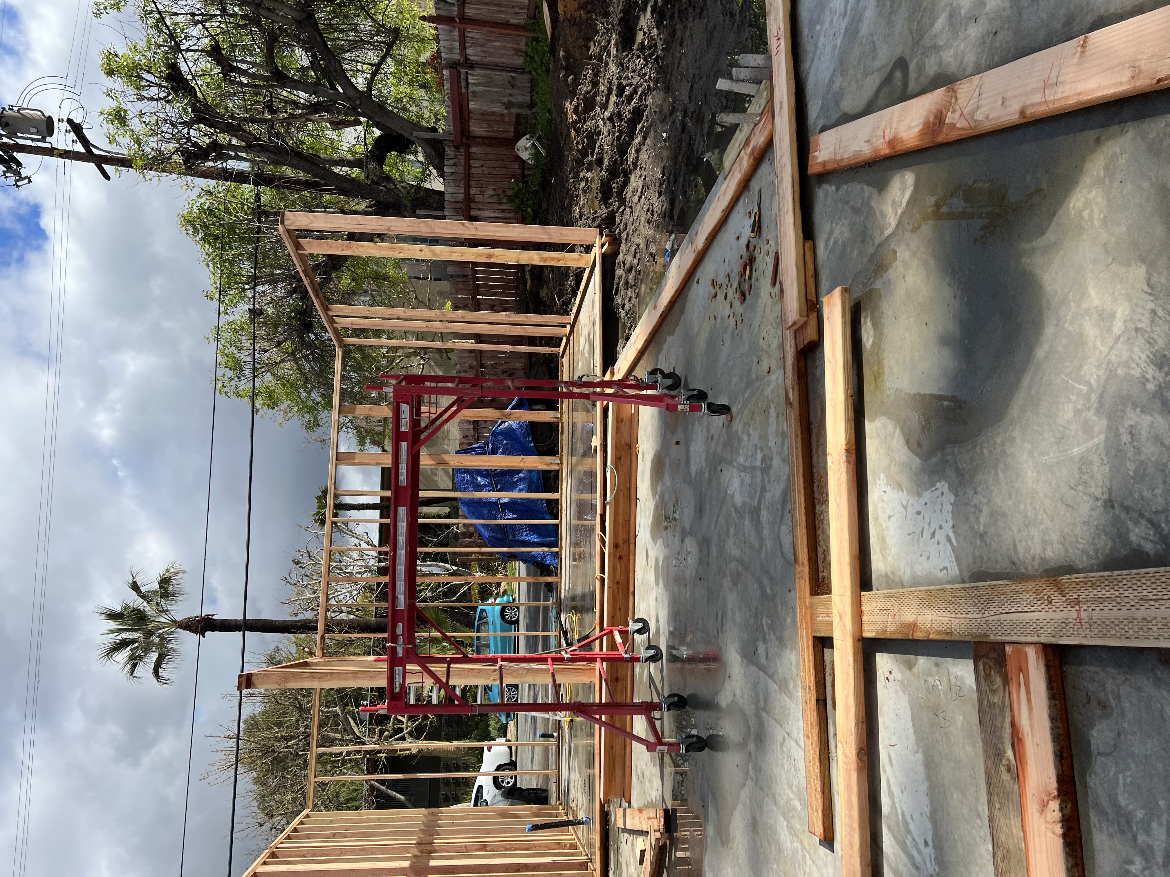 ADU foundation slab with wall framing and rolling scaffold stands