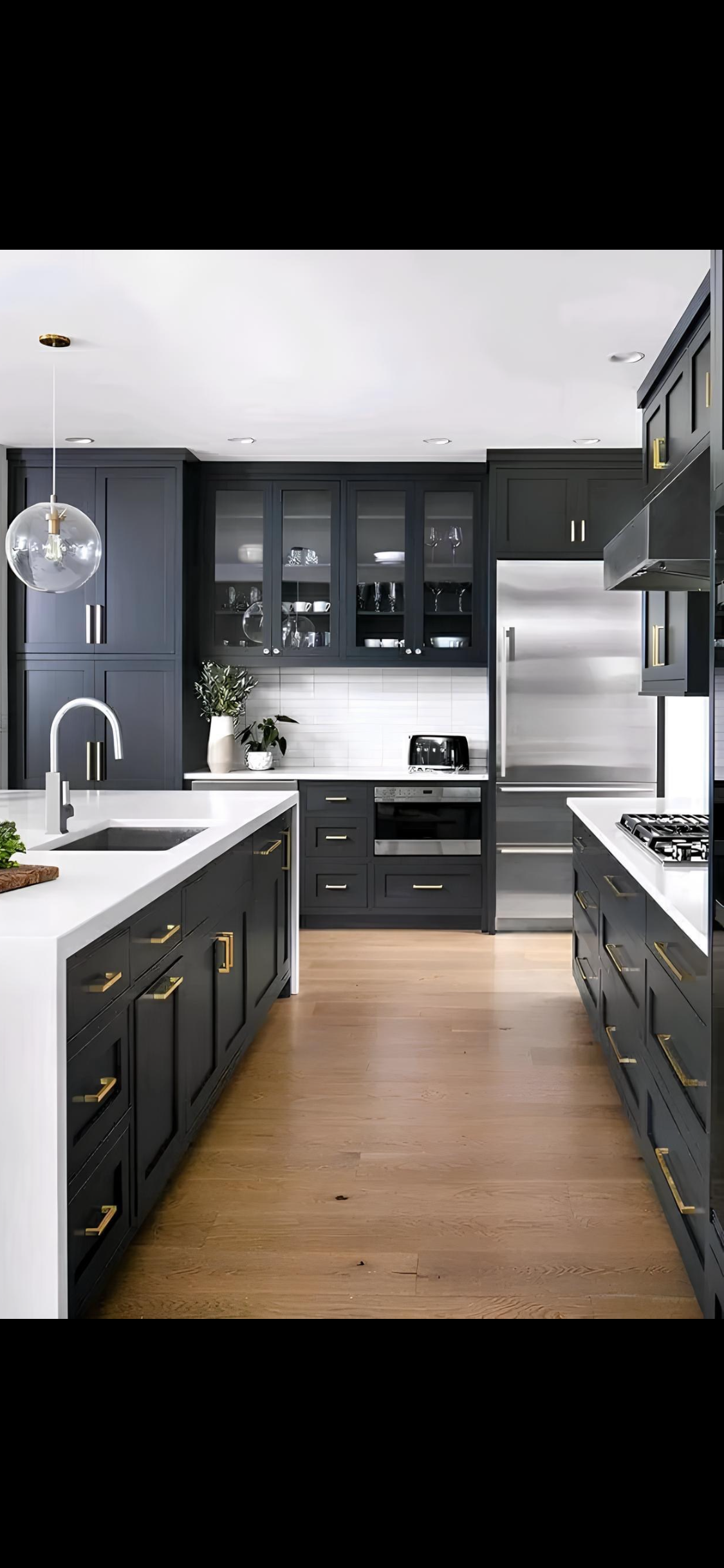 Modern kitchen with dark charcoal cabinetry, brushed gold hardware, and waterfall island