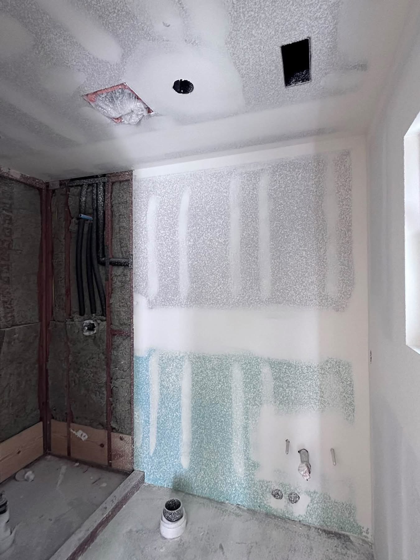 ADU bathroom corner with exposed studs, insulation, and plumbing rough-in