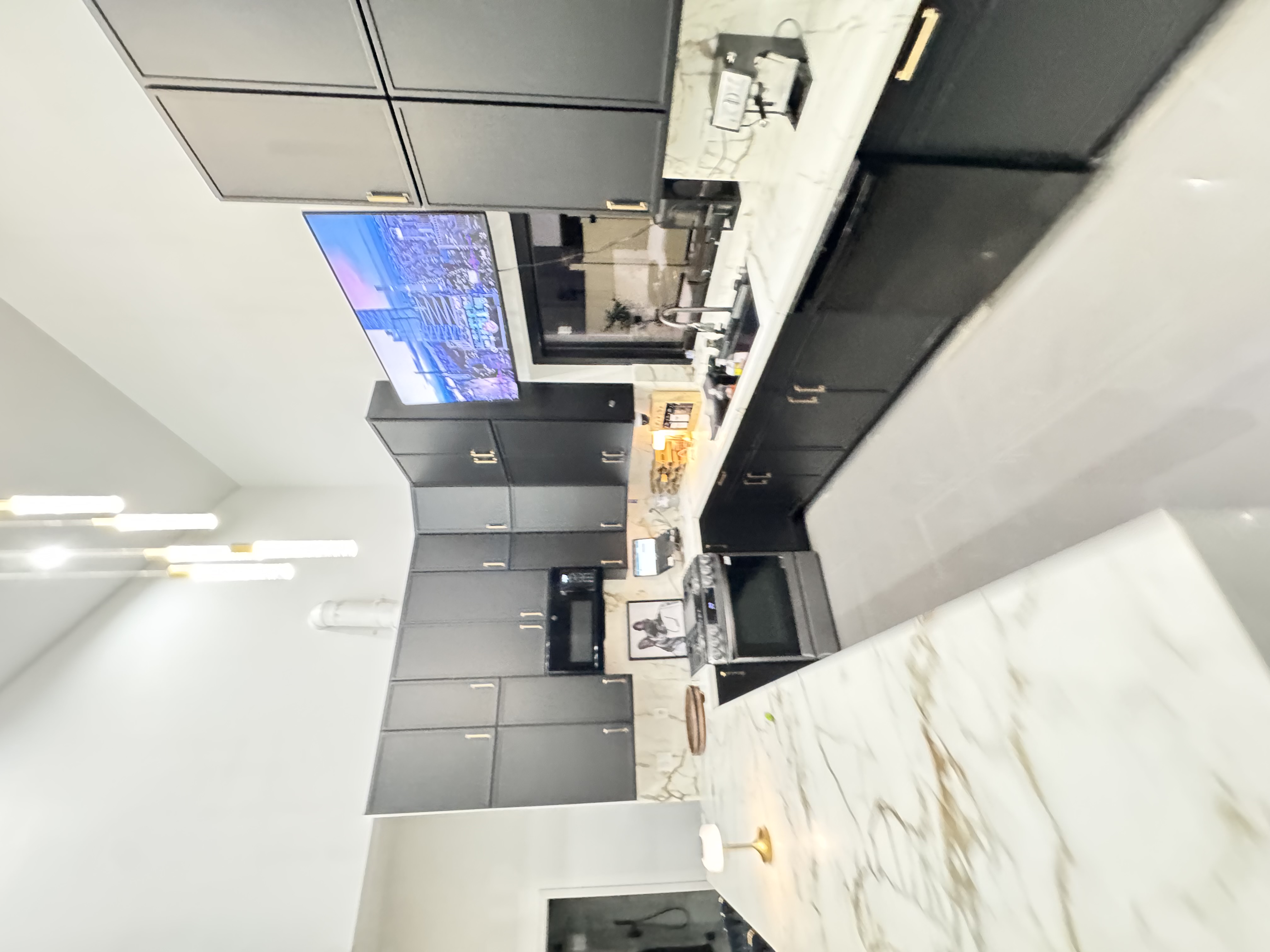 Kitchen with charcoal cabinetry, marble waterfall island, and cityscape wall display