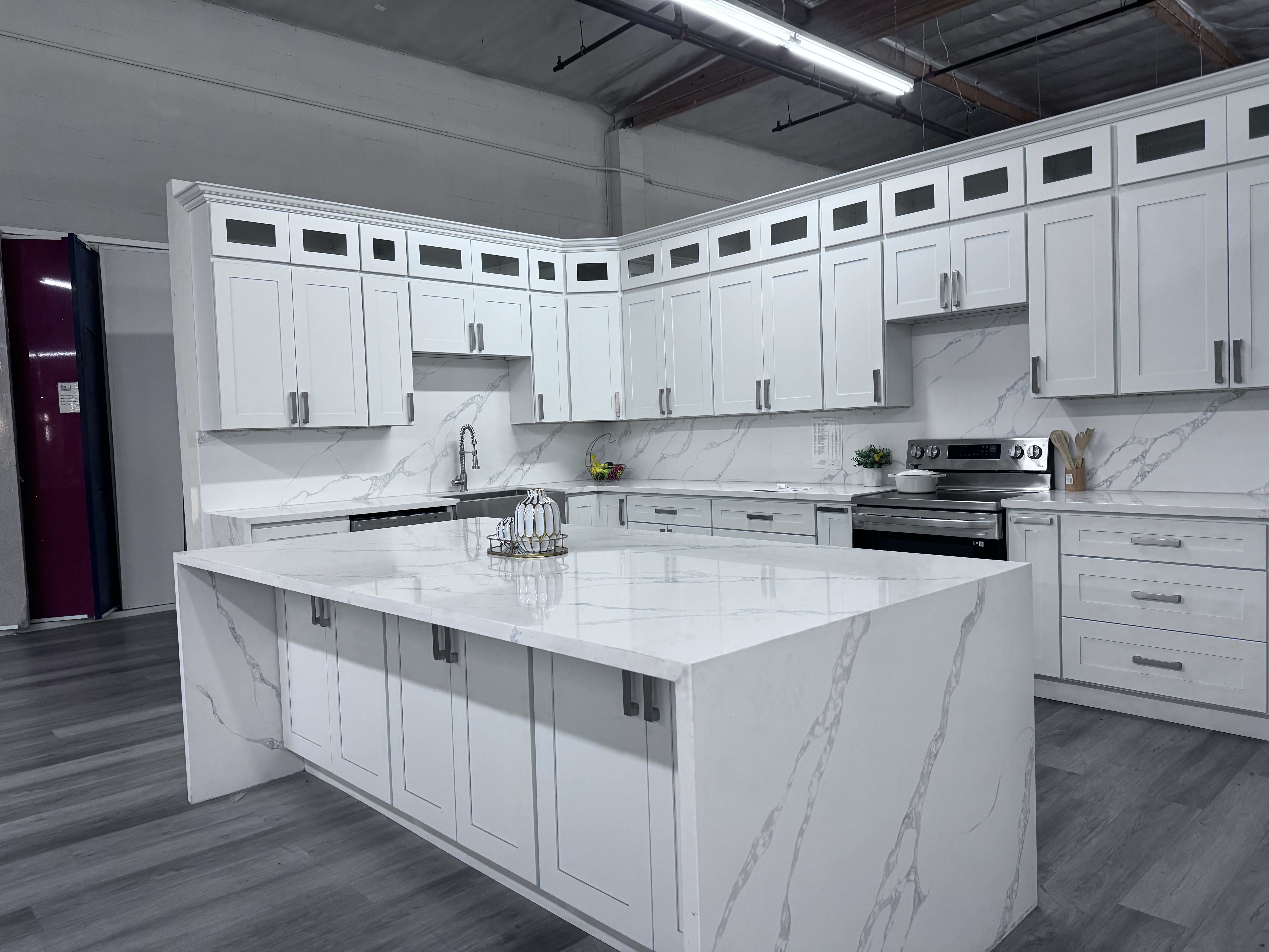 White Shaker kitchen with Calacatta quartz waterfall island and stainless steel range