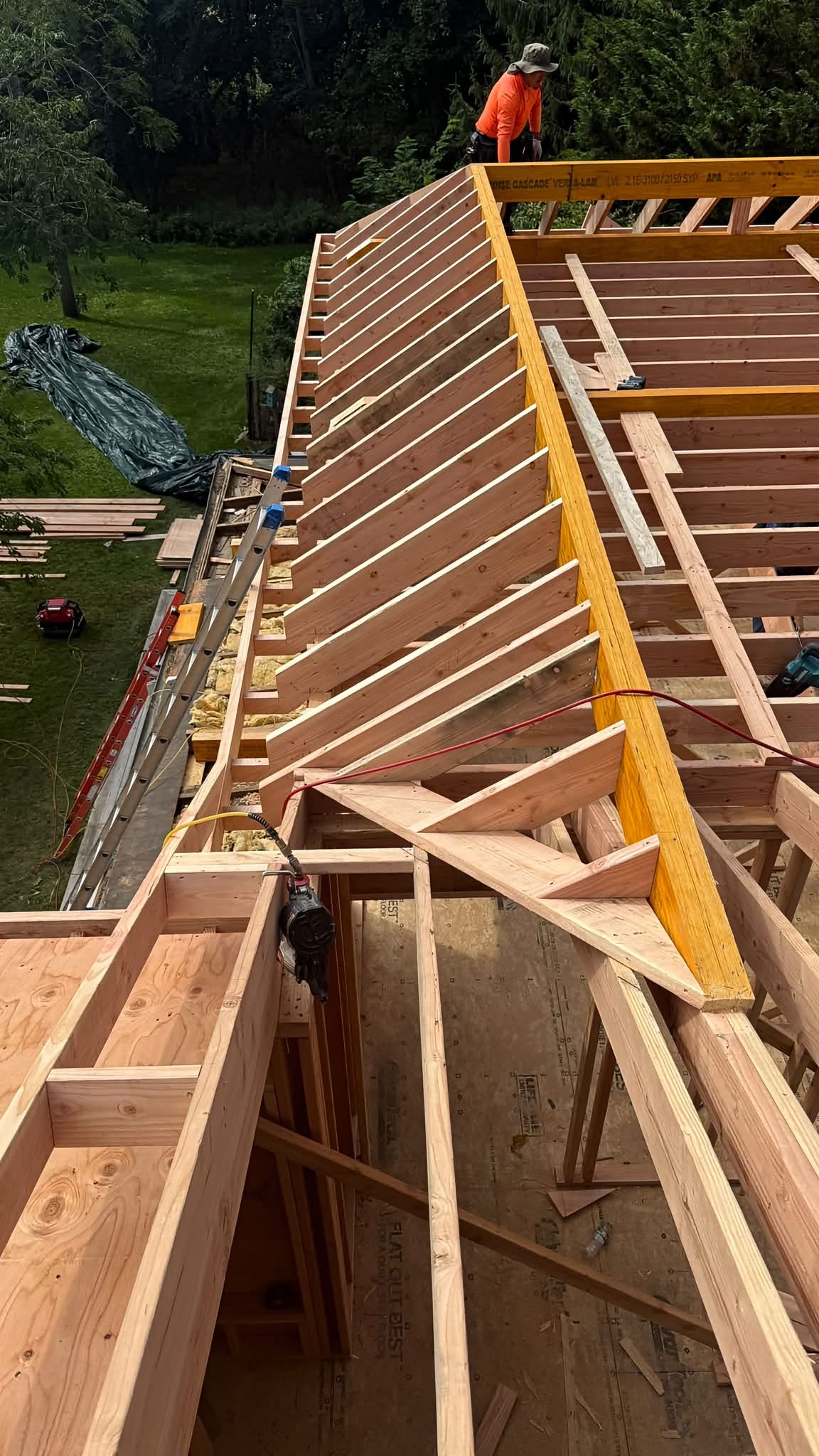 ADU hip roof framing with LVL ridge board and worker in orange