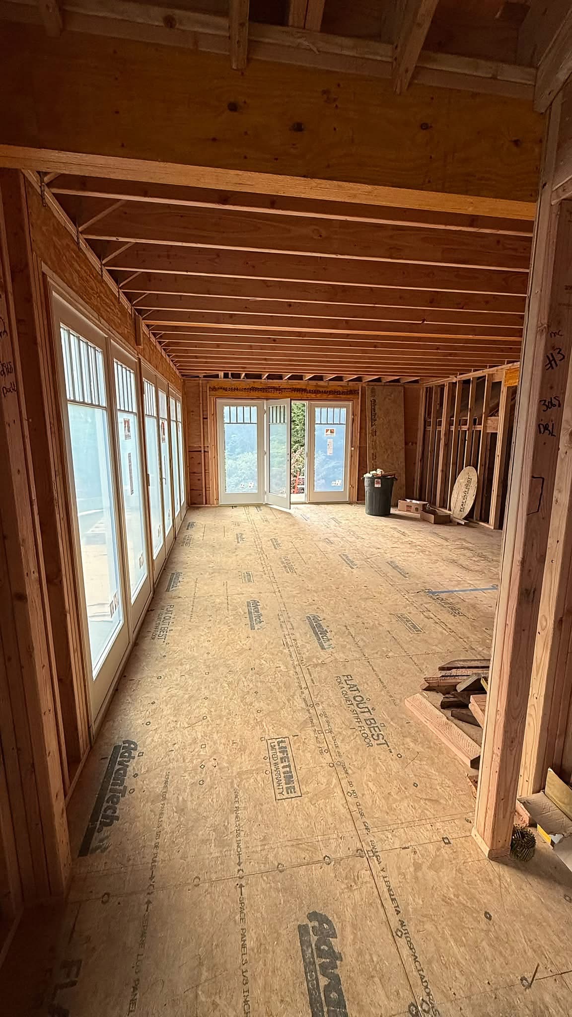 Interior of ADU with ceiling joists, windows and open French doors