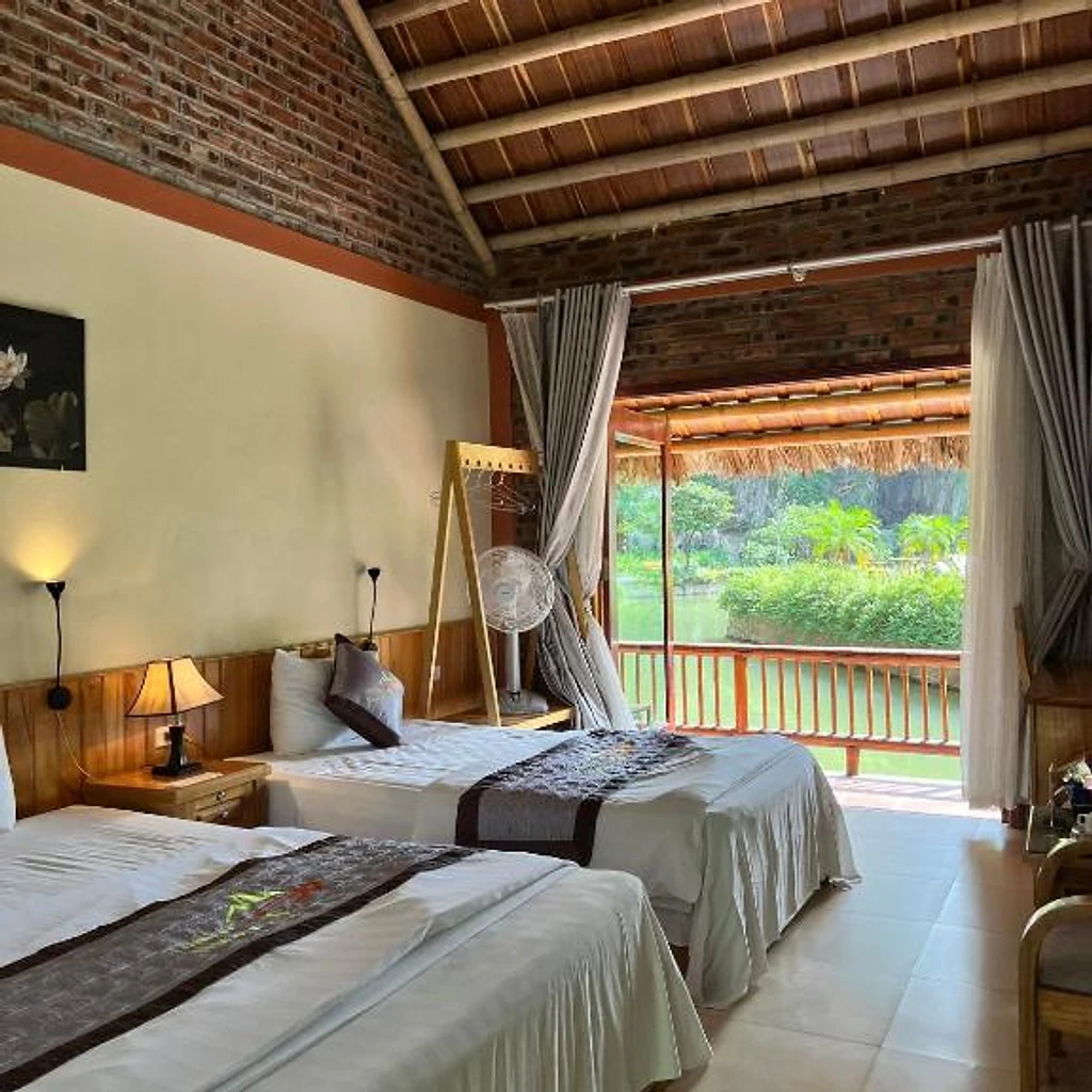 Rustic twin bedroom with vaulted ceiling and balcony at Tam Coc Nature
