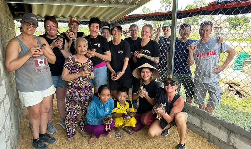 The whole Way To Travel group together at the build site, holding chicks
